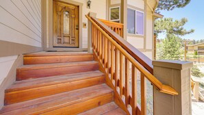 Una escalera de madera con barandilla que lleva a una puerta principal con detalles decorativos.