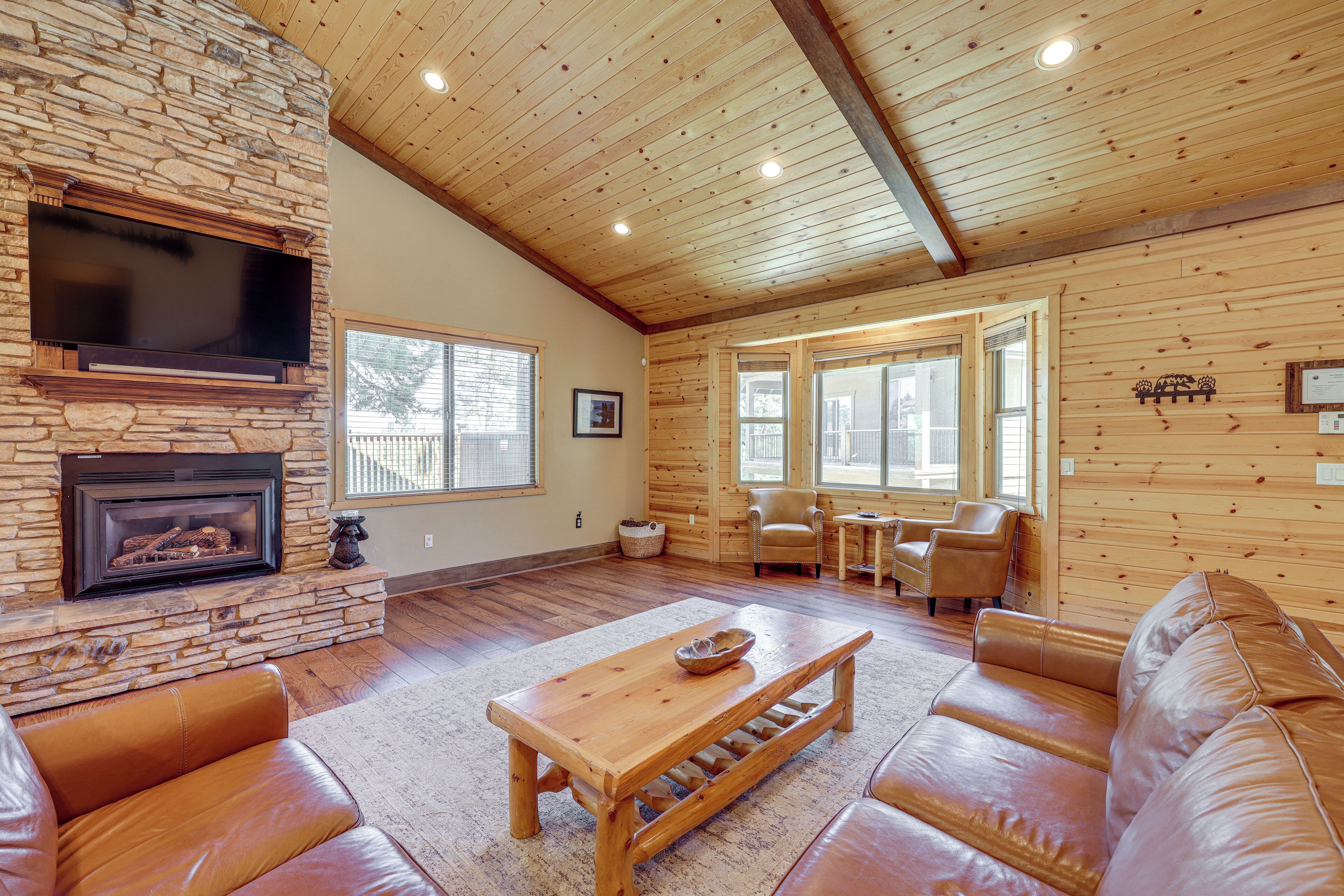 A spacious living room with a stone fireplace, leather sofas, and a wooden coffee table.