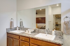 A bathroom with two sinks, a large mirror, wooden cabinets, and a towel rack.