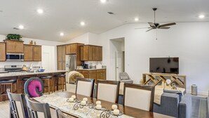 A modern kitchen with wooden cabinets, a central island, and a dining area with a table set for six. - 9 Mi to Dtwn Bakersfield: Pet-friendly Home (Bakersfield)