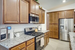 A kitchen with wooden cabinets, stainless steel appliances, granite countertops, and a framed sign on the wall. - 9 Mi to Dtwn Bakersfield: Pet-friendly Home (Bakersfield)