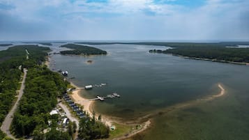 An aerial view of a coastal area with a dock, a road, and a row of houses along the shoreline.