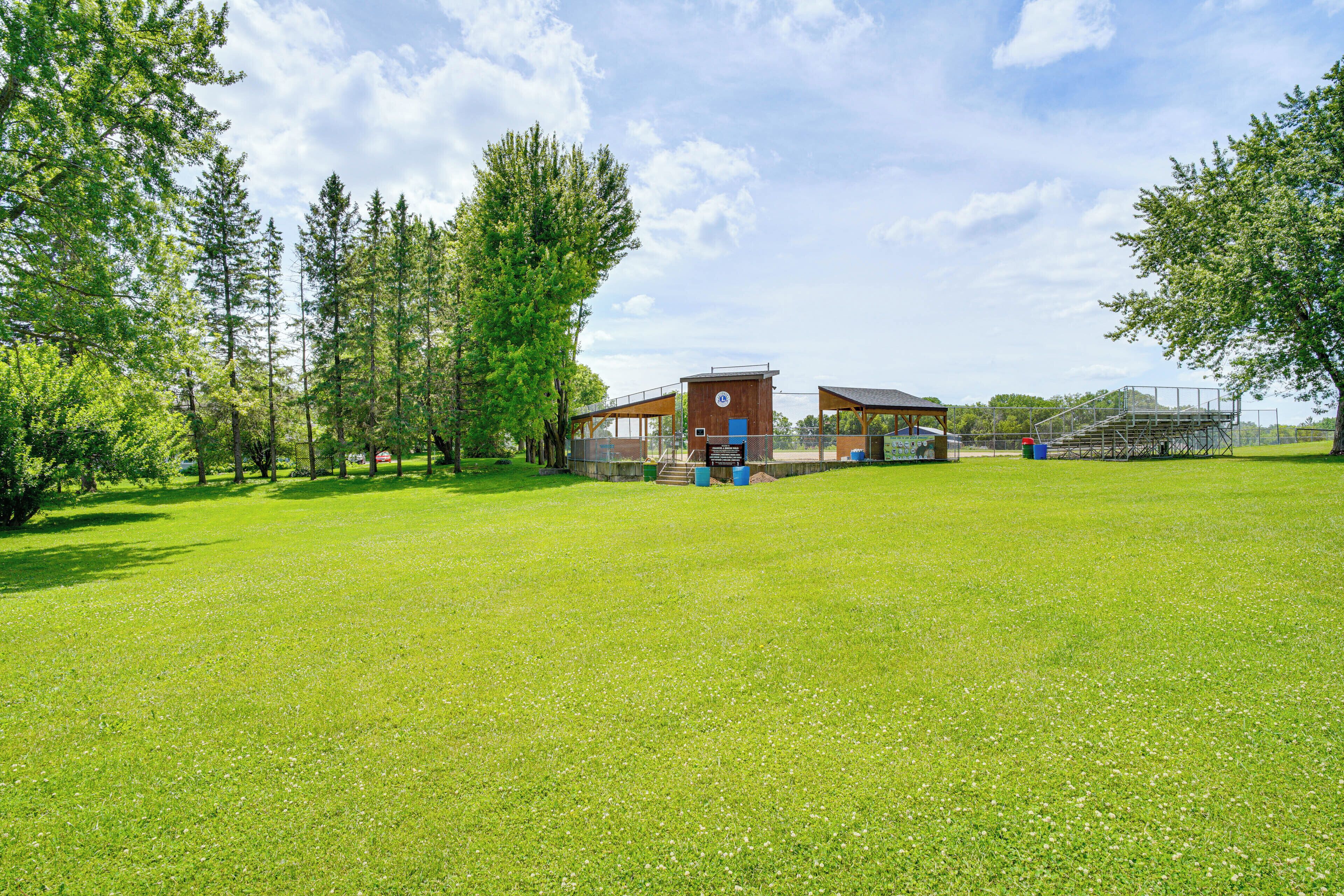 A grassy field with a building that has a blue door and a red roof.