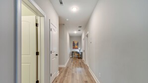 A hallway with wooden flooring, white walls, and a door at the end.