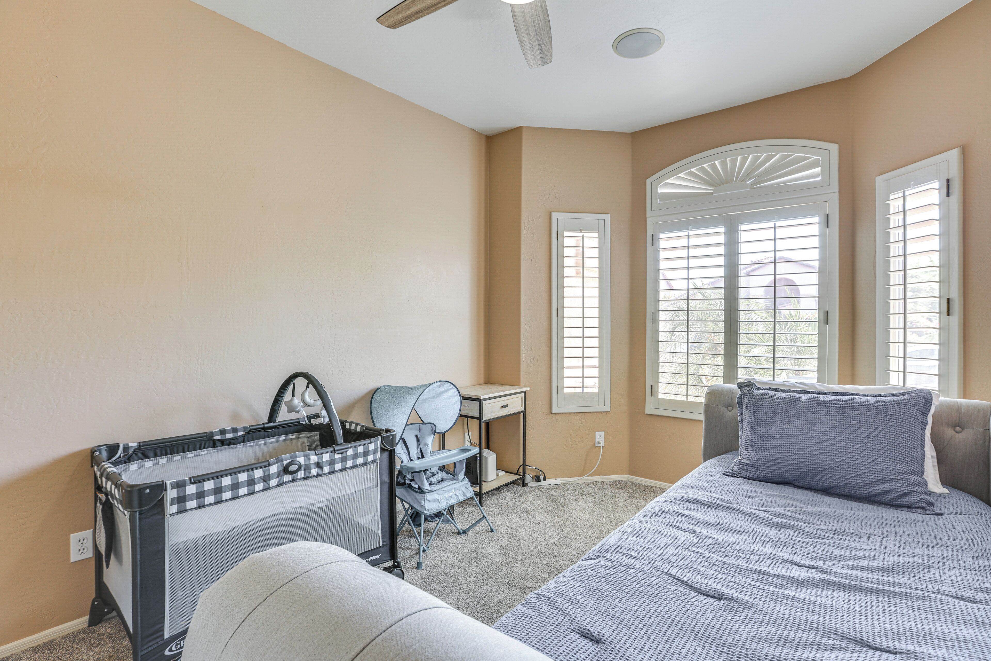 A bedroom with a bed, a desk, a chair, and a crib.