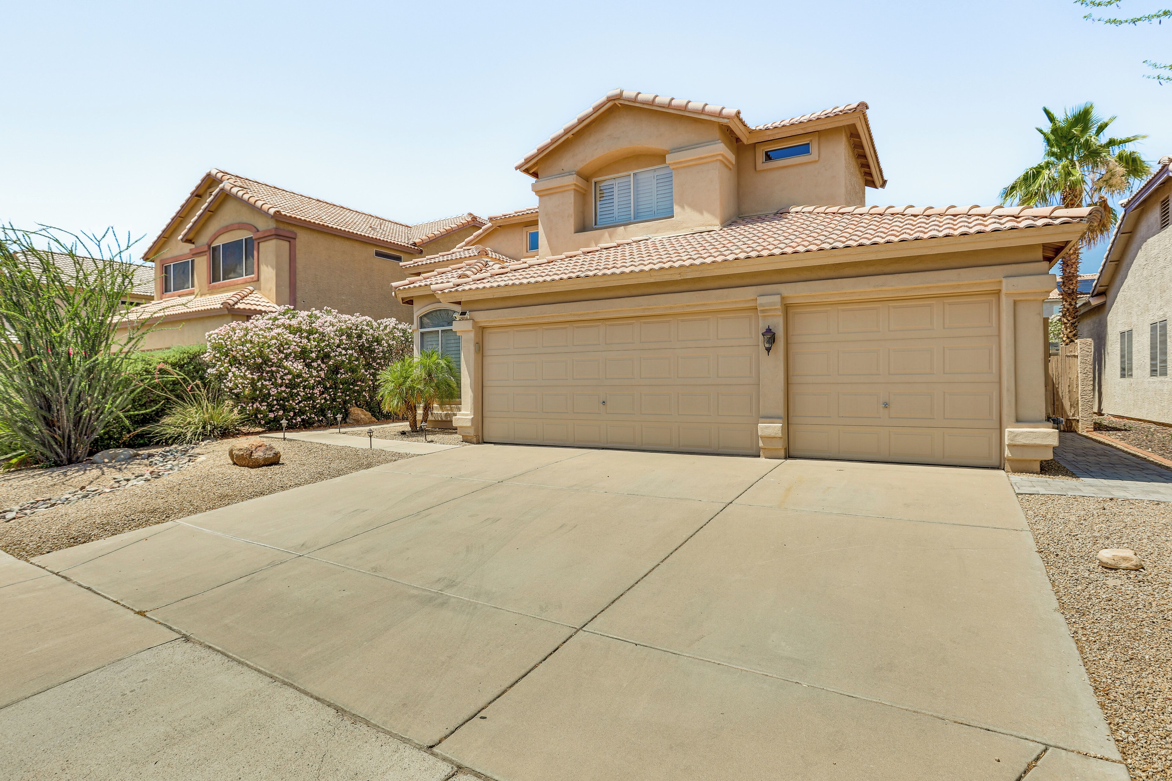A residential house with a large garage, a well-maintained driveway, and a landscaped garden with various plants.