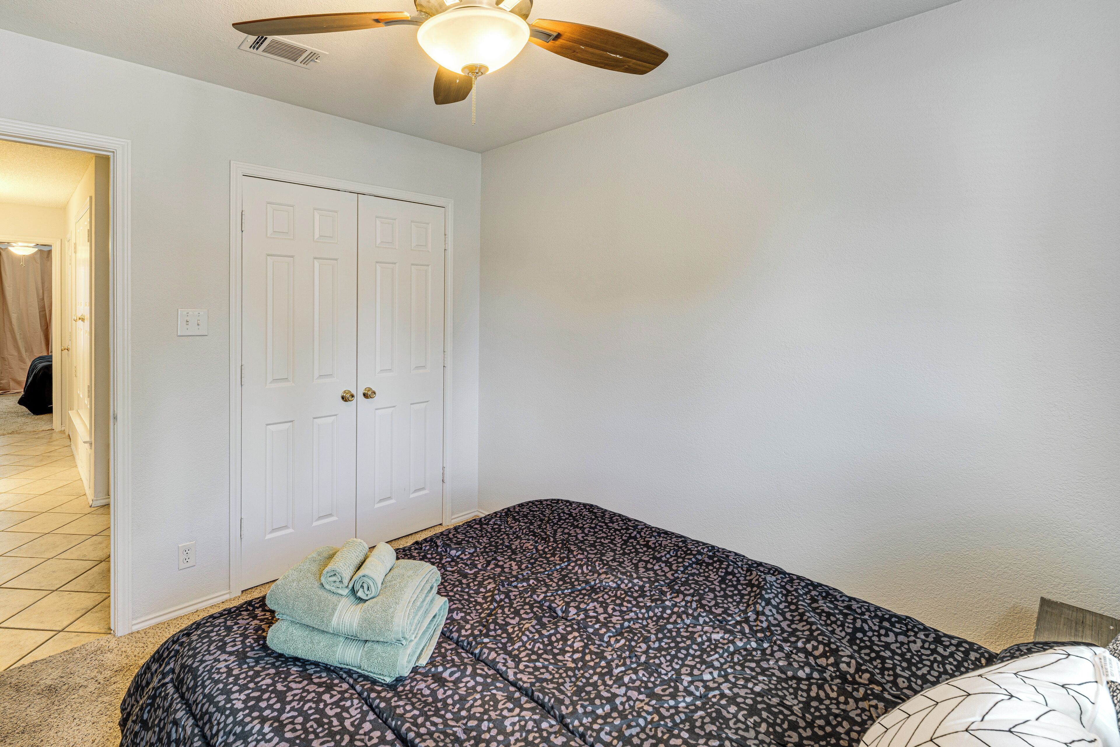 A bedroom with a bed, a ceiling fan, and a door.
