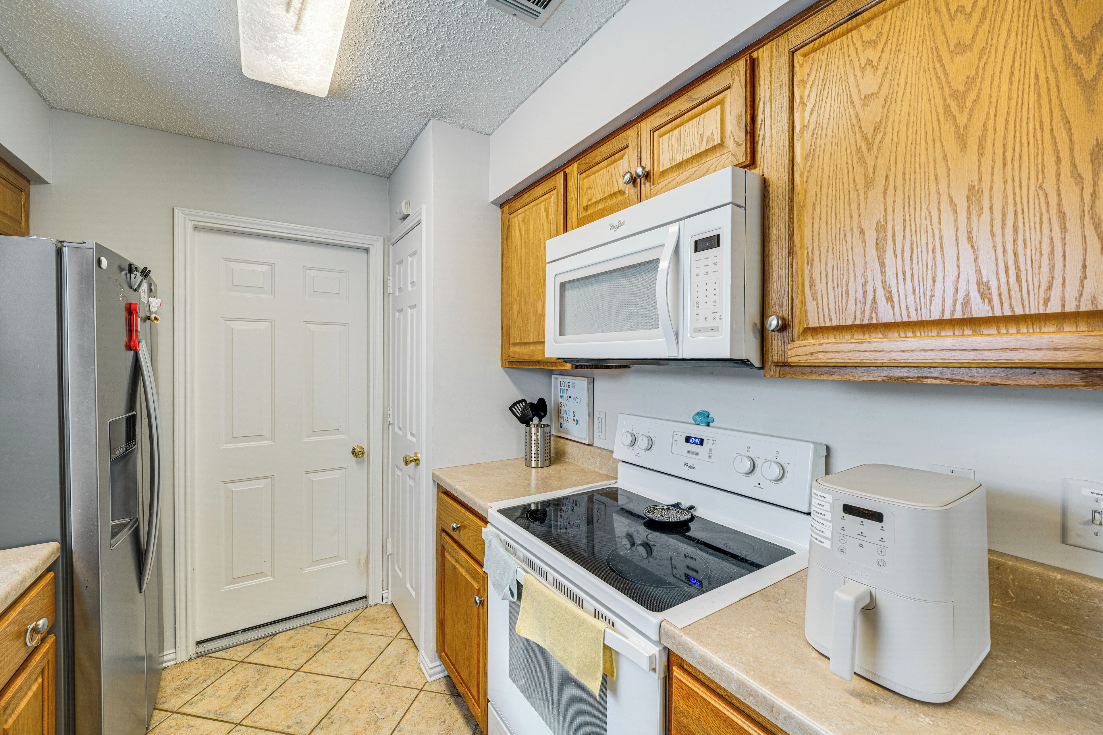 A kitchen with a refrigerator, microwave, oven, and toaster.
