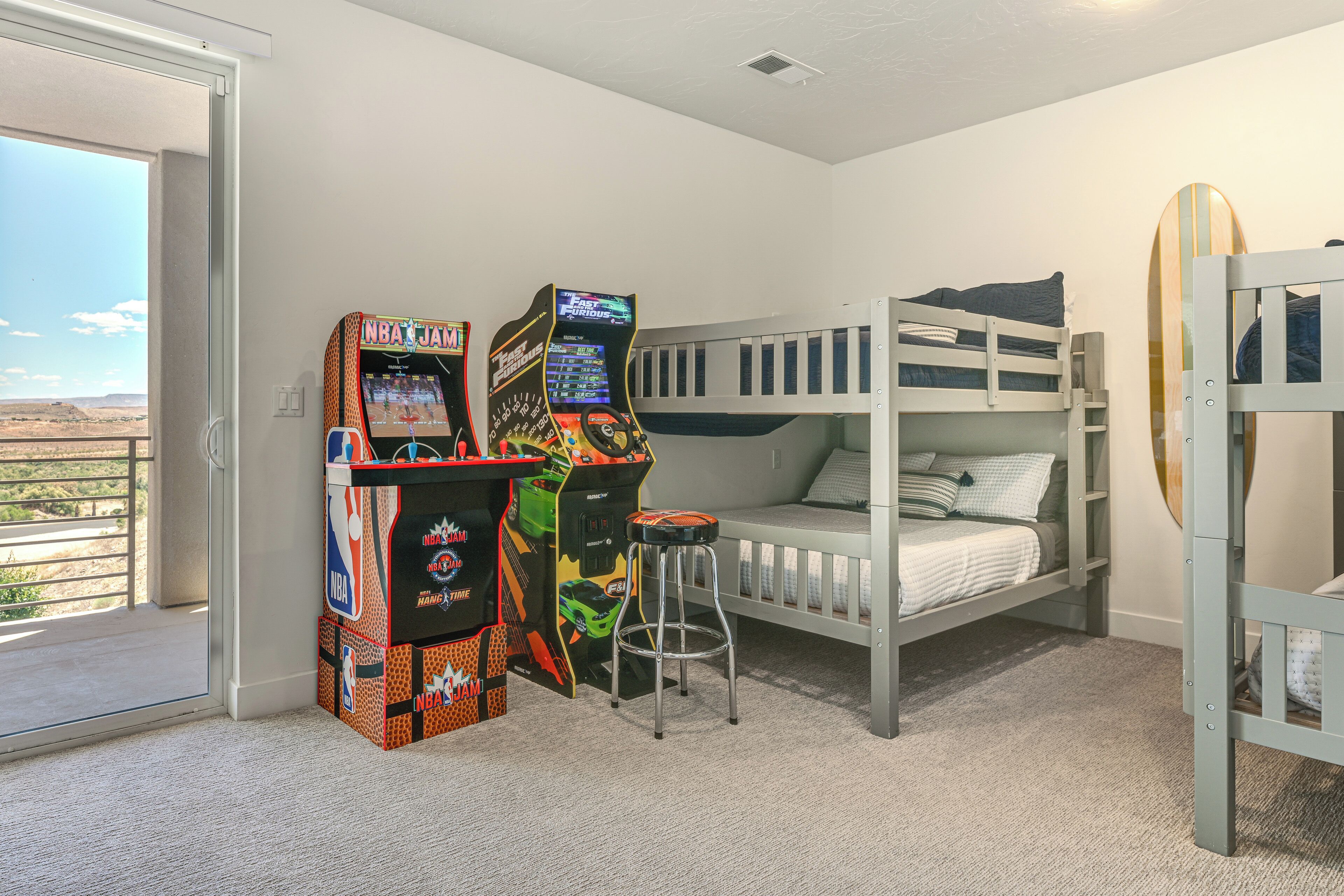 A room with bunk beds, a gaming console, and a surfboard.