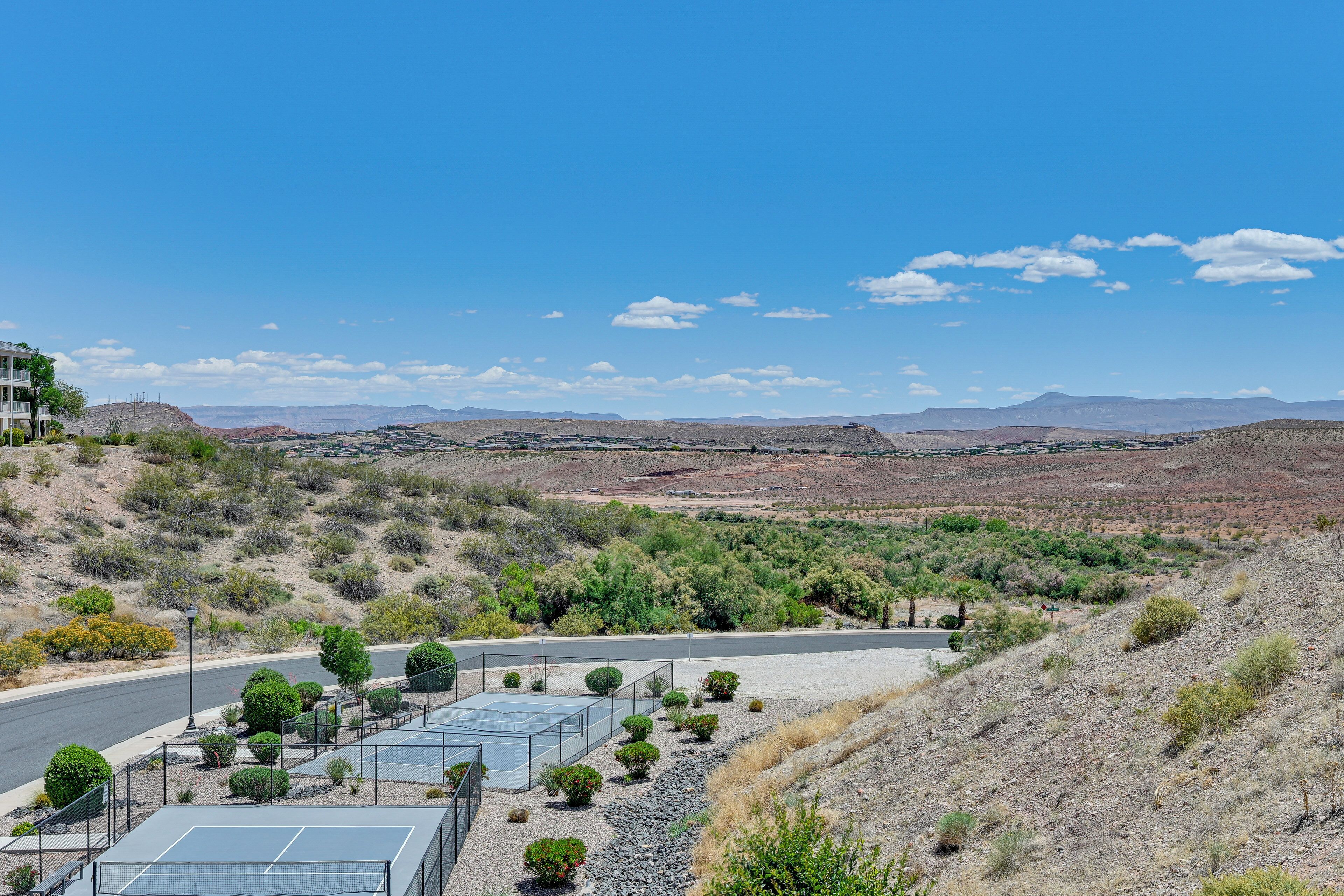 A desert landscape with a paved road, solar panels, and sparse vegetation.