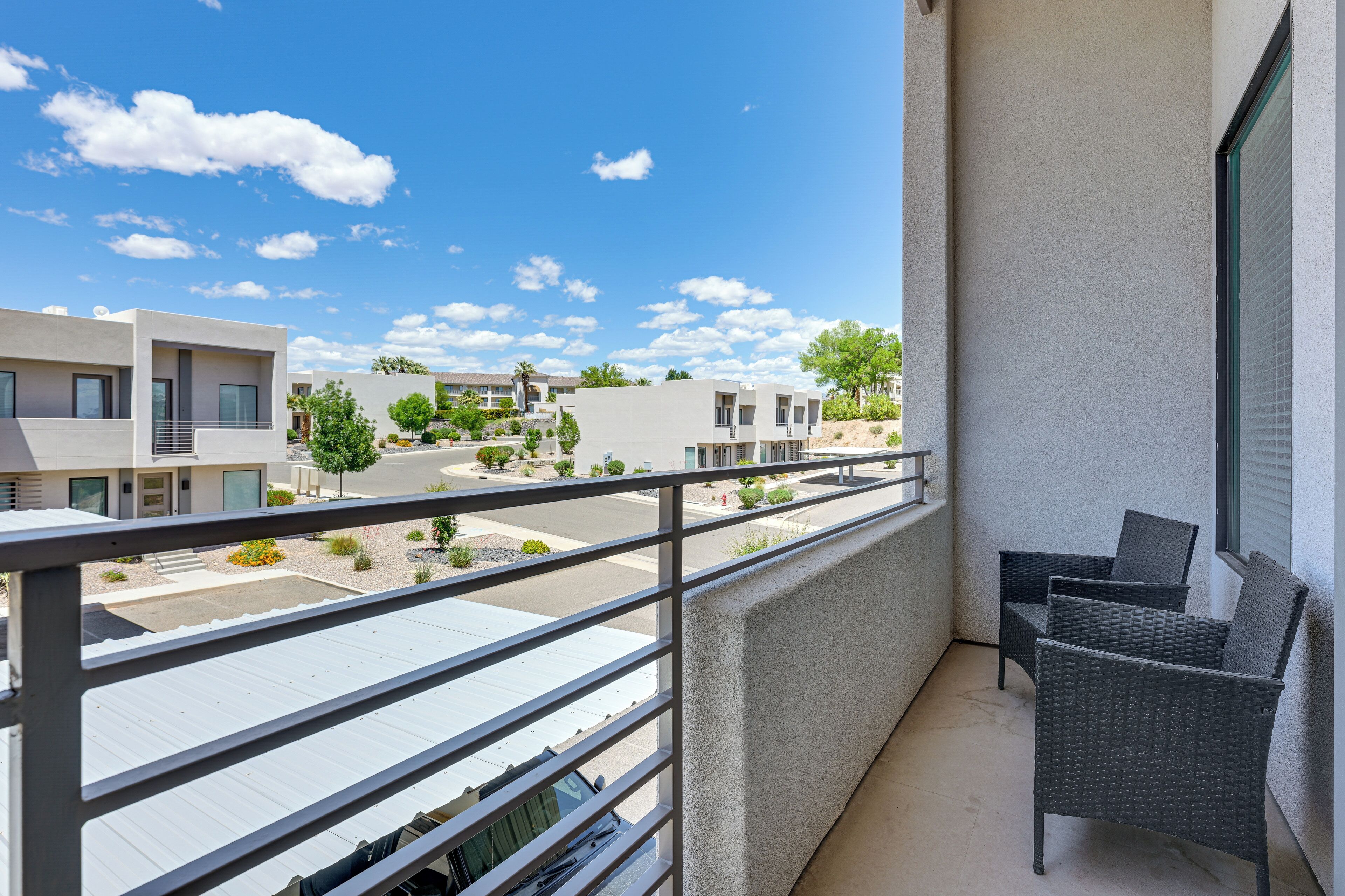 Un balcon donnant sur un quartier résidentiel, avec des bâtiments modernes et un ciel dégagé.