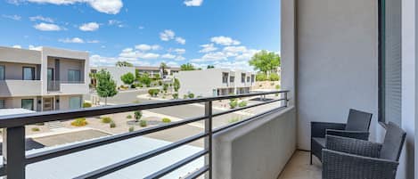 Un balcon donnant sur un quartier résidentiel, avec des bâtiments modernes et un ciel dégagé.