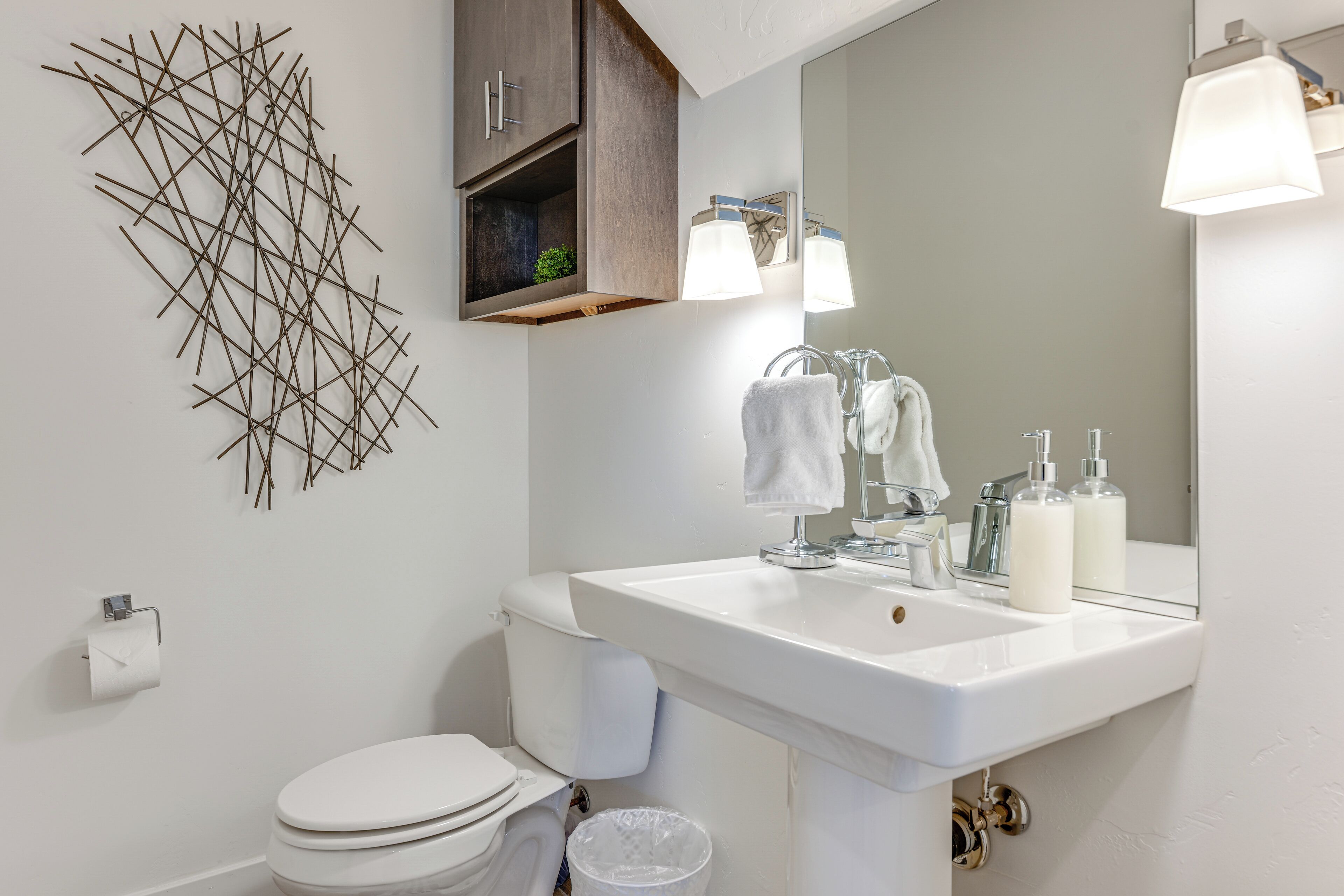 A modern bathroom with a white sink, a toilet, and a wall-mounted mirror.