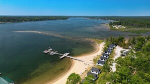 A lakeside property with a dock, beach, and row of cabins. - Beach & Dock Access! Upper Peninsula Cabin Retreat (Cedarville)