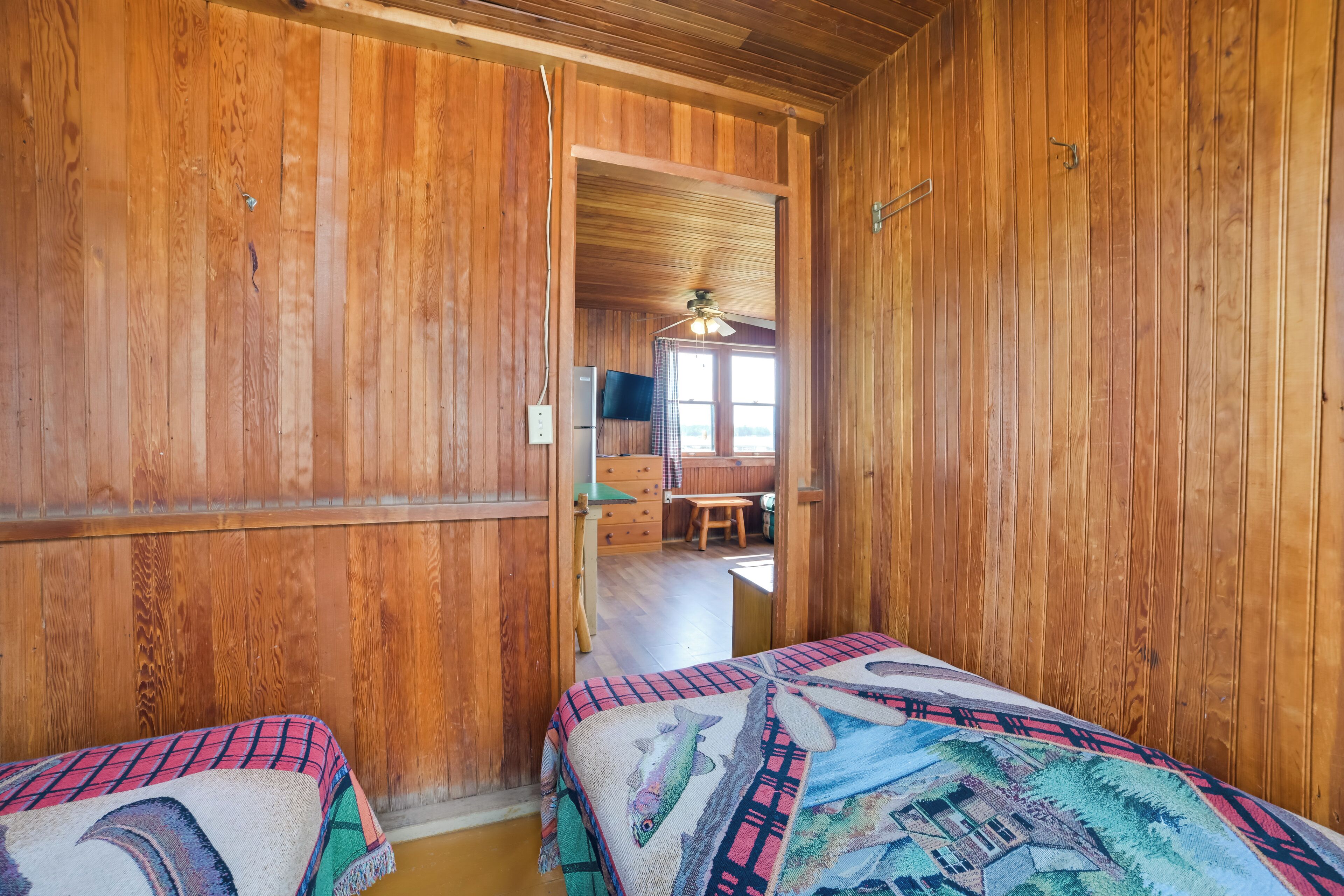A wooden room with two beds, a desk, and a television.