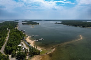 An aerial view of a coastal area with a dock, a road, and a row of houses along the shoreline. - Resort Cabin On Lake Huron! Pets Welcome (Cedarville)