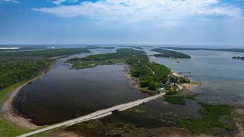 An aerial view of a coastal area with a bridge connecting two landmasses, surrounded by water and greenery.