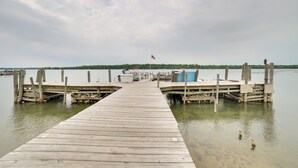A wooden pier extending into calm water, with a docked boat and an American flag on a pole at the end. - Resort Cabin On Lake Huron! Pets Welcome (Cedarville)