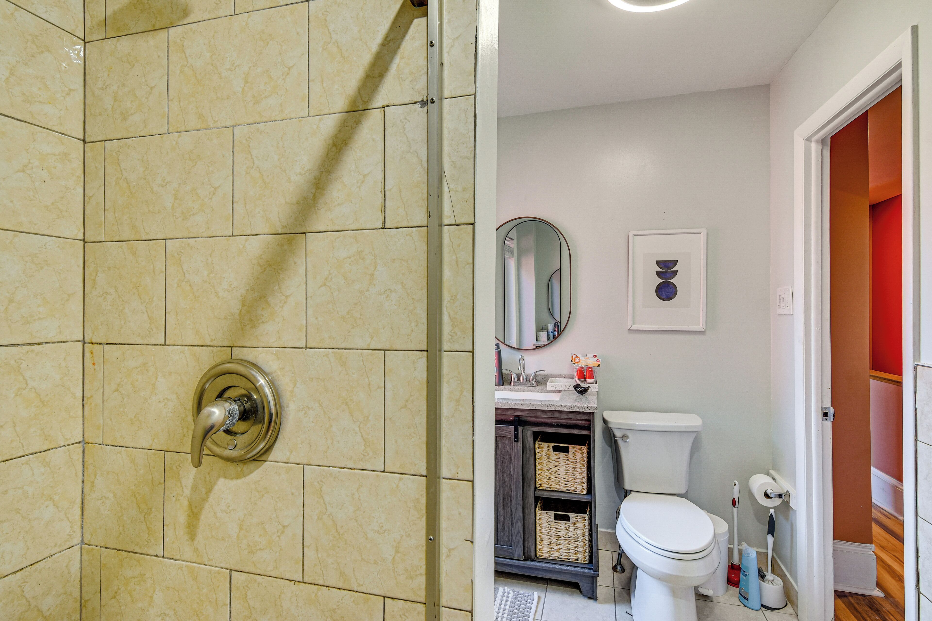 Un bagno con doccia, toilette, lavandino e mobiletti contenitori.