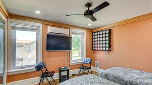 Une chambre avec deux lits, un ventilateur de plafond, une télévision et une fenêtre avec des stores.