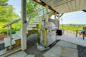 A covered outdoor area with a stainless steel grill, steps leading to a covered porch, and a view of the surrounding greenery. - Kennebec River Retreat < 5 Mi to Popham Beach (Phippsburg)