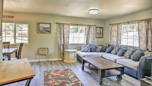 A cozy living room with a sofa, a coffee table, and a dining table. There are windows with curtains, a small cabinet, and a rug on the floor. - Kingston Sleeper: Unique Stay Near Silver Mountain (Kingston)