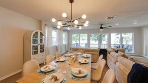 A dining area with a long table set for four, a built-in bookshelf, and a seating area with a sofa and chairs. - Waterfront Cedar Creek Lake Gem: Near Marina! (Kemp)