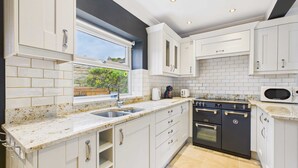 Una cocina moderna con armarios blancos, encimera de granito, horno empotrado y ventana con vistas a zonas verdes.