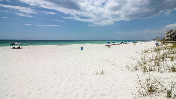 A beach with a clear sky, a sandy shore, and a few beach umbrellas.