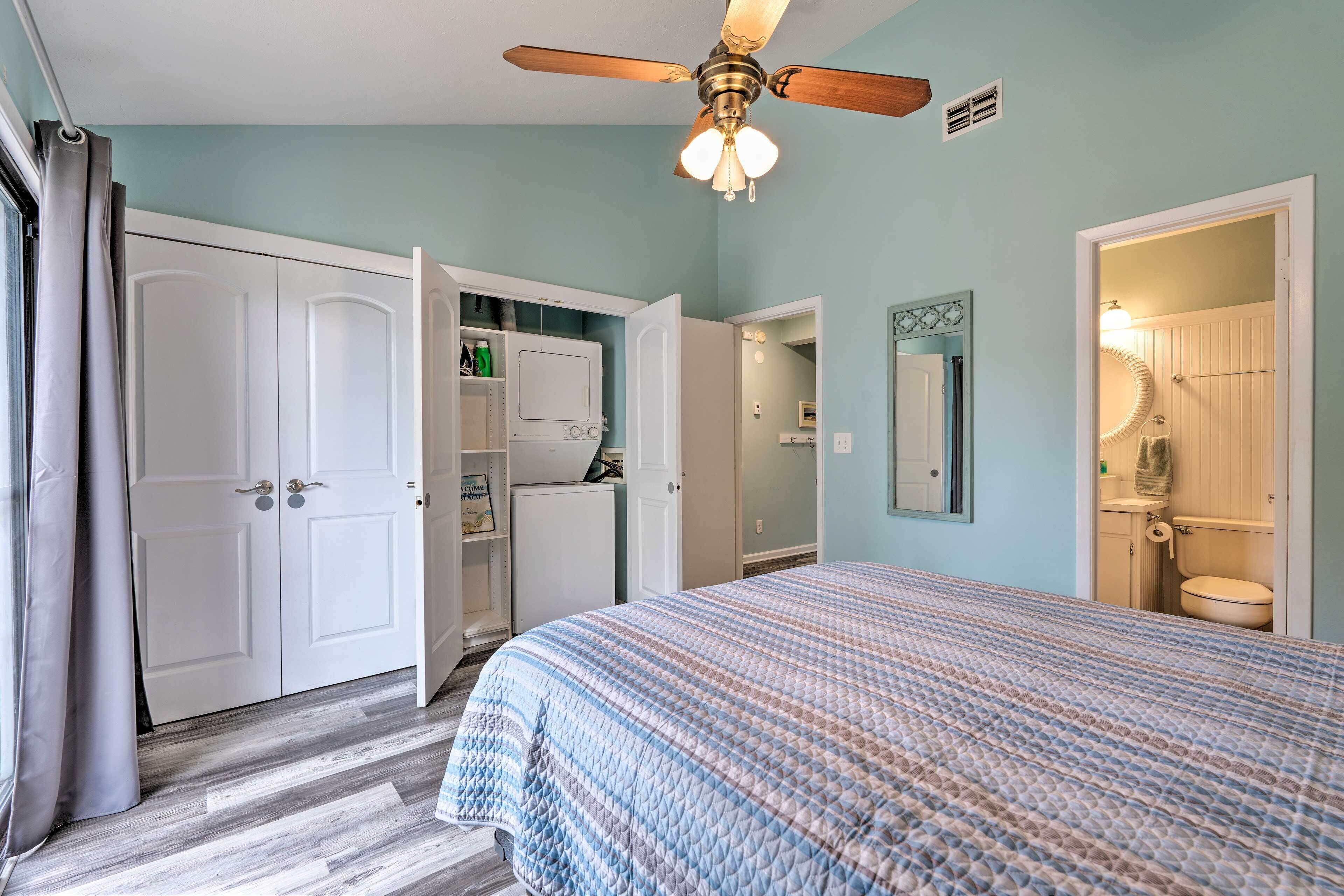 A bedroom with a bed, a ceiling fan, a wardrobe, and a bathroom visible through an open door.