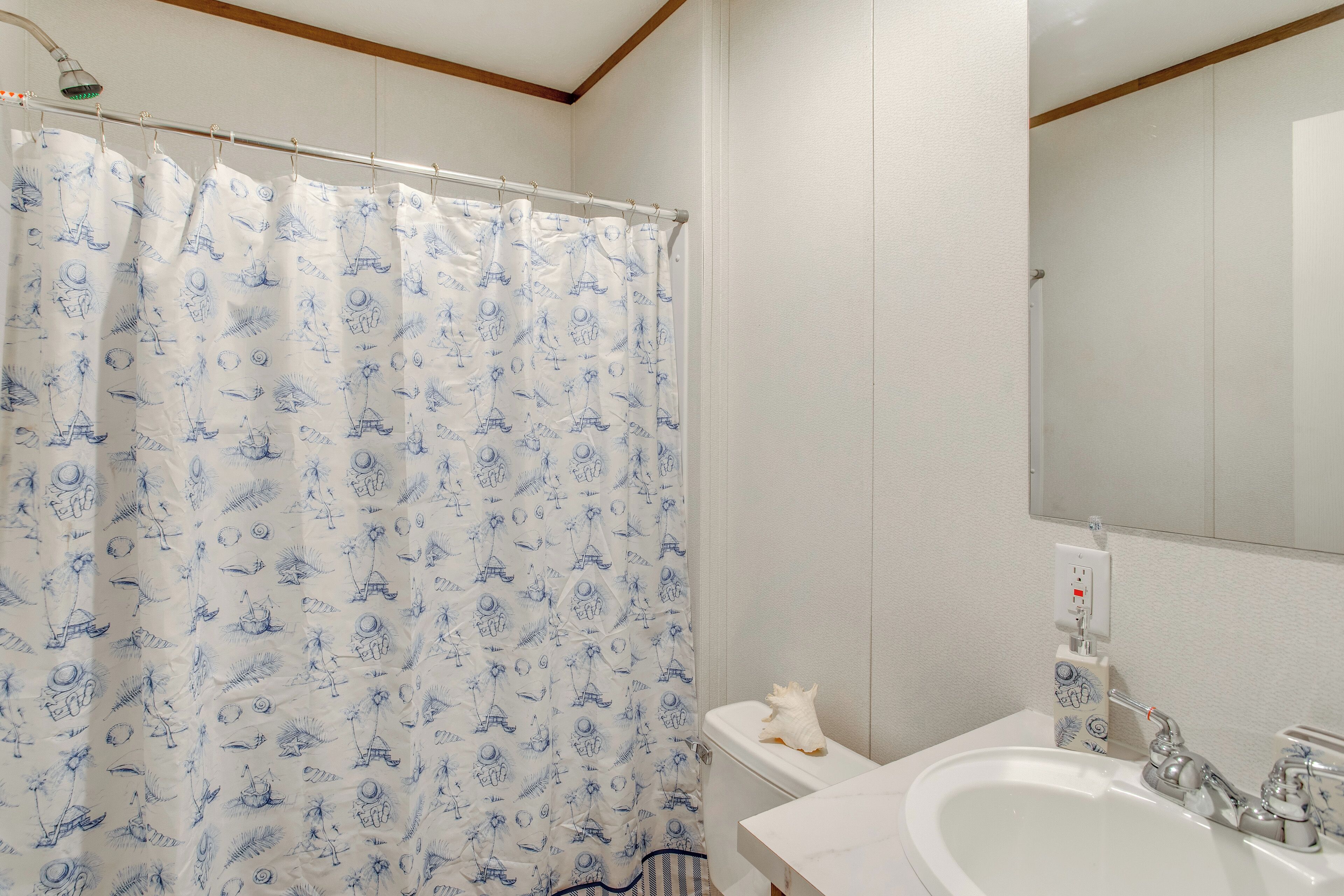 A bathroom with a shower curtain featuring blue patterns, a white sink, and a mirror above the sink.