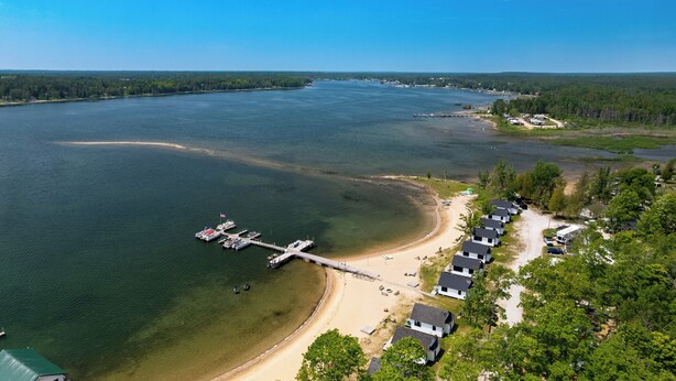 Propiedad frente al lago con muelle, playa y fila de cabañas.