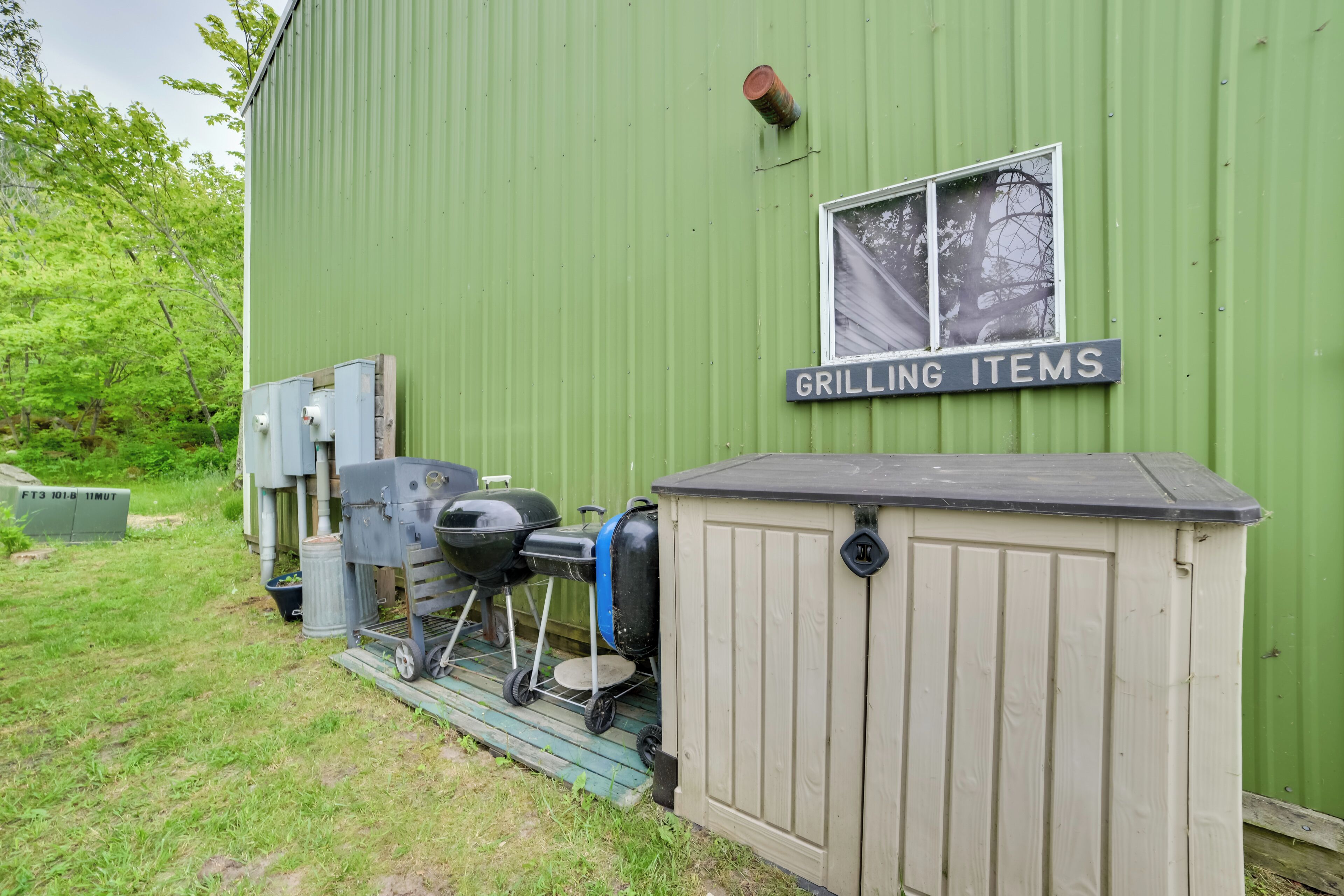 A green building with a sign reading "GRILLING ITEMS" and a small shed.