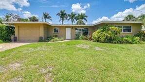 A two-story house with a garage, surrounded by a well-maintained lawn and palm trees.