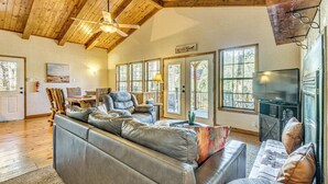 A spacious living room with a large leather sectional sofa, a wooden ceiling, and a fireplace. - Hot Tub Haven w/ Game Room & Grill in Ruidoso! (Ruidoso)