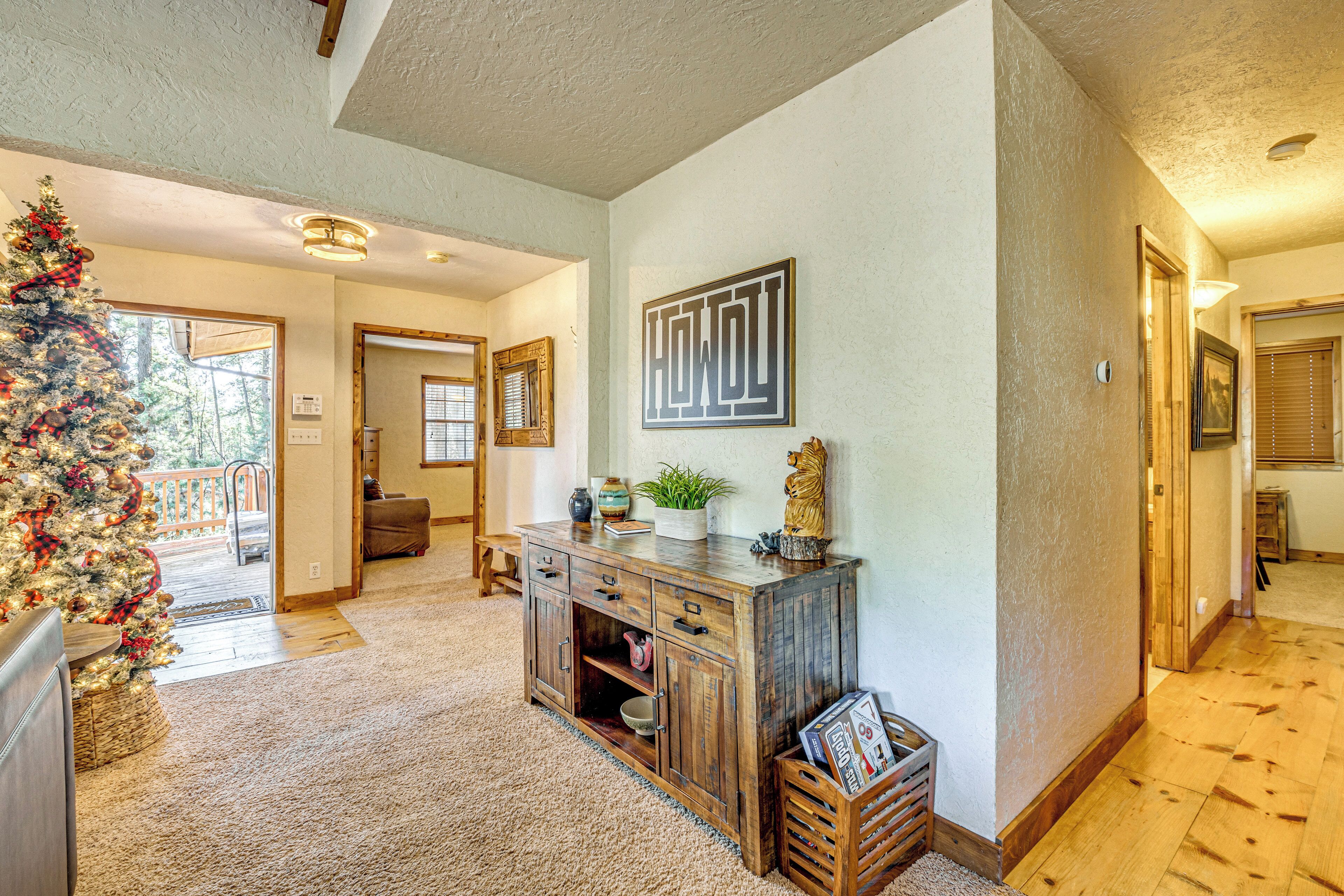 A spacious living area with a wooden cabinet, a Christmas tree, and a framed artwork on the wall.