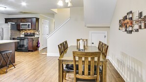 A spacious kitchen with modern appliances, a dining area with wooden chairs, and a staircase leading to another level. - 7 Mi to Dtwn Augusta: Townhome Near Shops & Eats! (Grovetown)