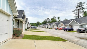 A row of single-story houses with attached garages, a sidewalk, and parked cars. - 7 Mi to Dtwn Augusta: Townhome Near Shops & Eats! (Grovetown)
