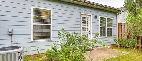A house with a front yard, a large air conditioning unit, and a wooden fence.