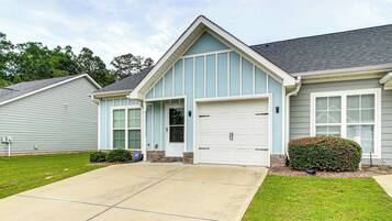 A two-story house with a garage, a front porch, and a well-maintained lawn.