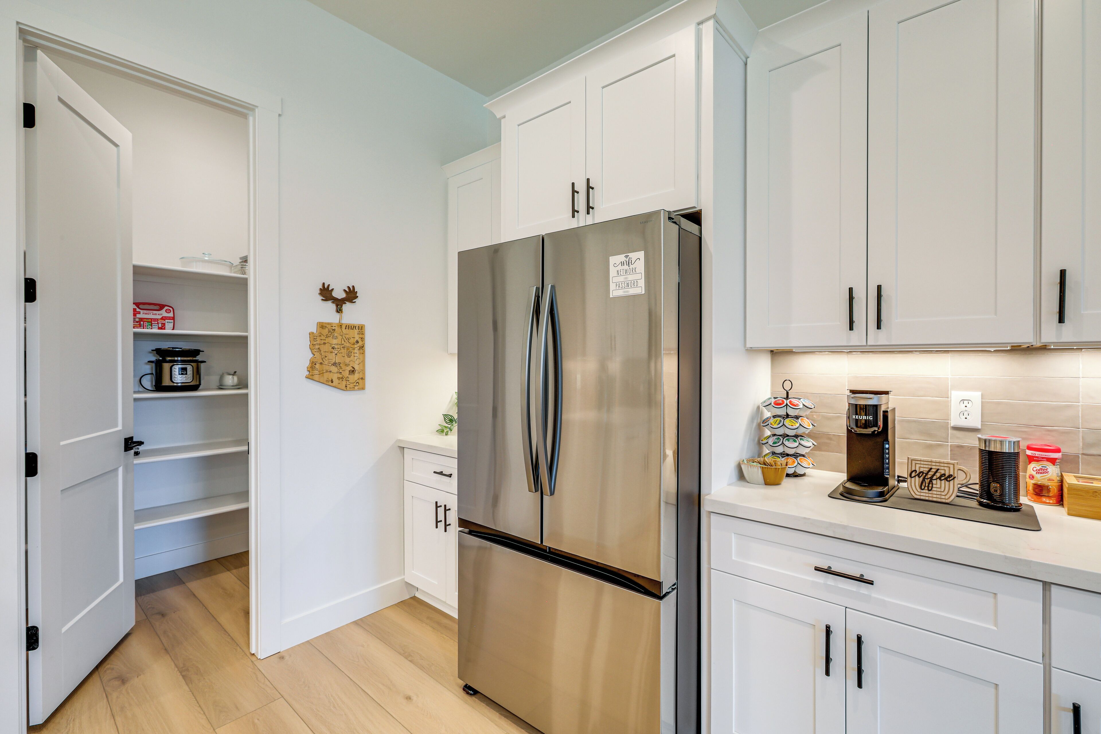 A modern kitchen with white cabinets, a stainless steel refrigerator, and a coffee maker on the counter.