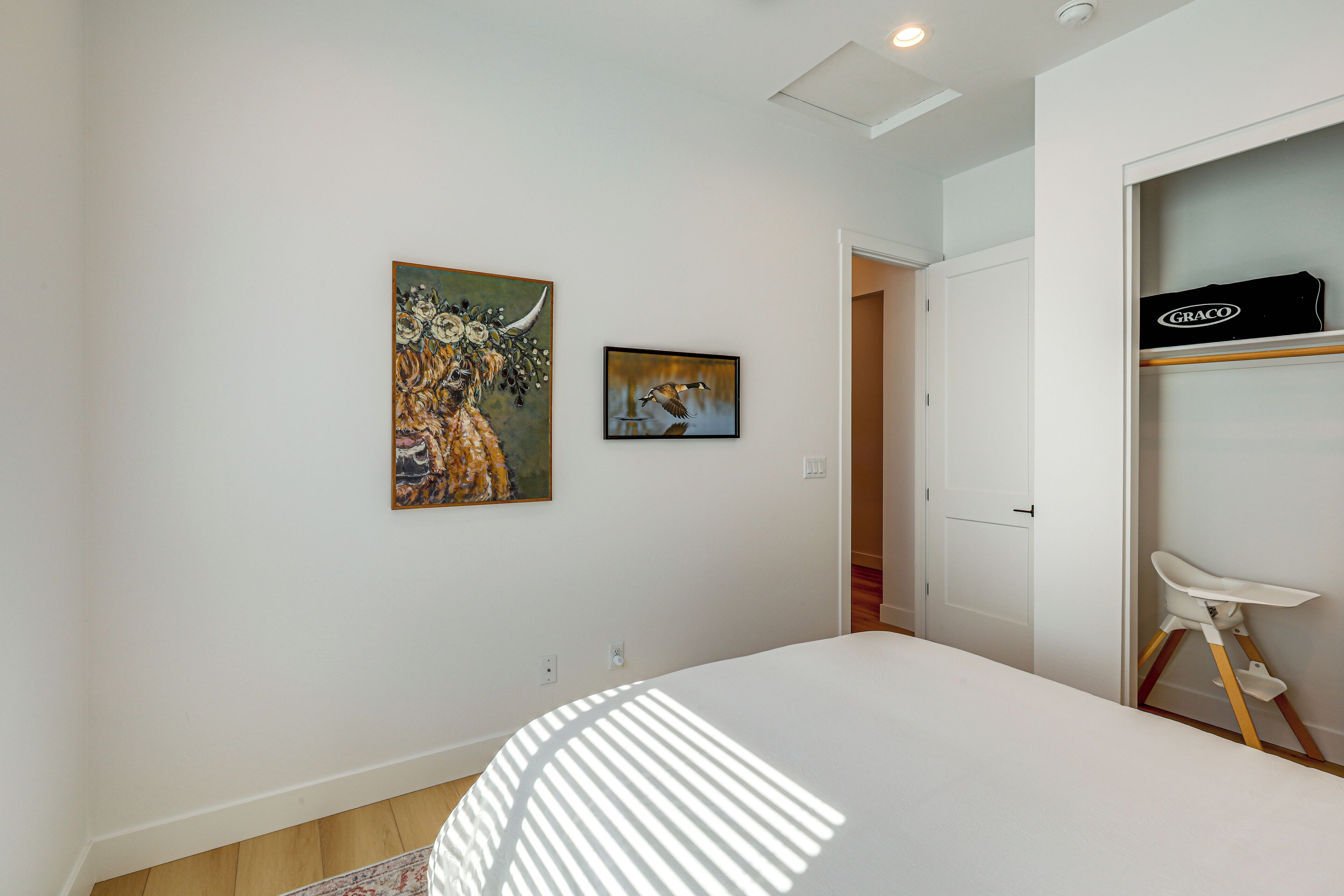 Un dormitorio con una cama, un armario blanco y dos cuadros en la pared.