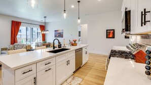 A modern kitchen with white cabinetry, a large island, stainless steel appliances, and pendant lighting.