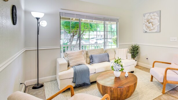 A living room with a beige sofa, a round wooden coffee table, and a floor lamp. - Clovis Family Home: Private Pool, Near Old Town! (Clovis)