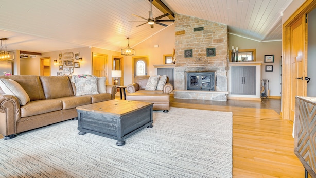 A spacious living room with a stone fireplace, leather sofas, and a wooden coffee table. - Hot Tub & Trail Access: Spacious Stockholm Retreat (Stockholm)