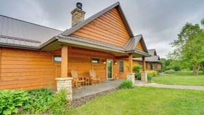 A wooden cabin with a covered porch, stone pillars, and a chimney. - Hot Tub & Trail Access: Spacious Stockholm Retreat (Stockholm)