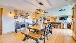 A spacious dining area with a wooden table and benches, a kitchen in the background, and a ceiling fan. - Hot Tub & Trail Access: Spacious Stockholm Retreat (Stockholm)
