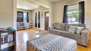 A spacious living room with a large sofa, a patterned ottoman, and a bookshelf. - Hixton Getaway: Near Lakes & Trails! (Hixton)