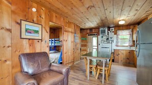 A wooden cabin interior with a dining table, chairs, a refrigerator, and a leather couch. - Complimentary Boat Rentals! Lake Huron Cabin (Cedarville)
