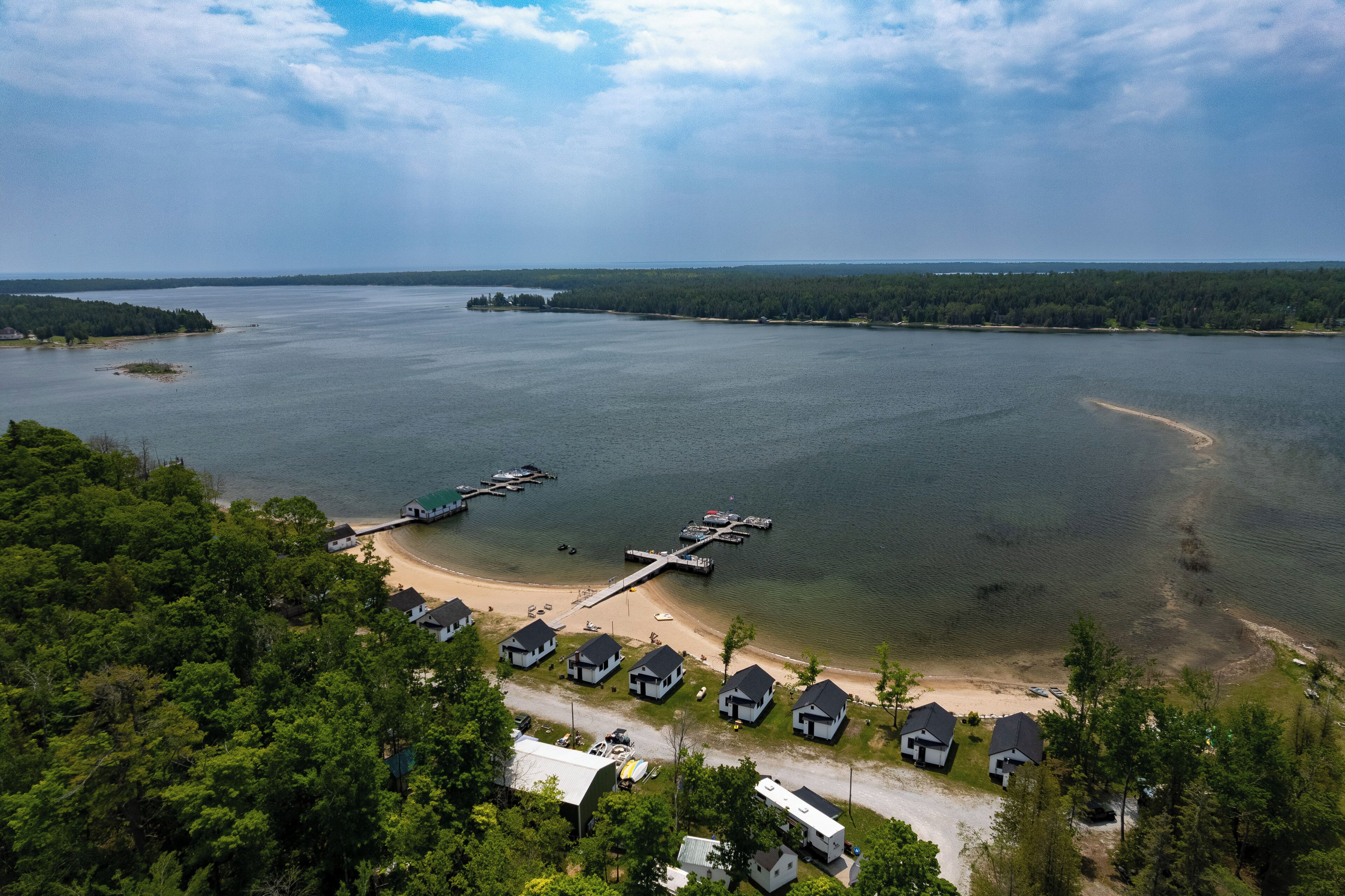 A lakeside property with several cabins, a dock, and a beach.
